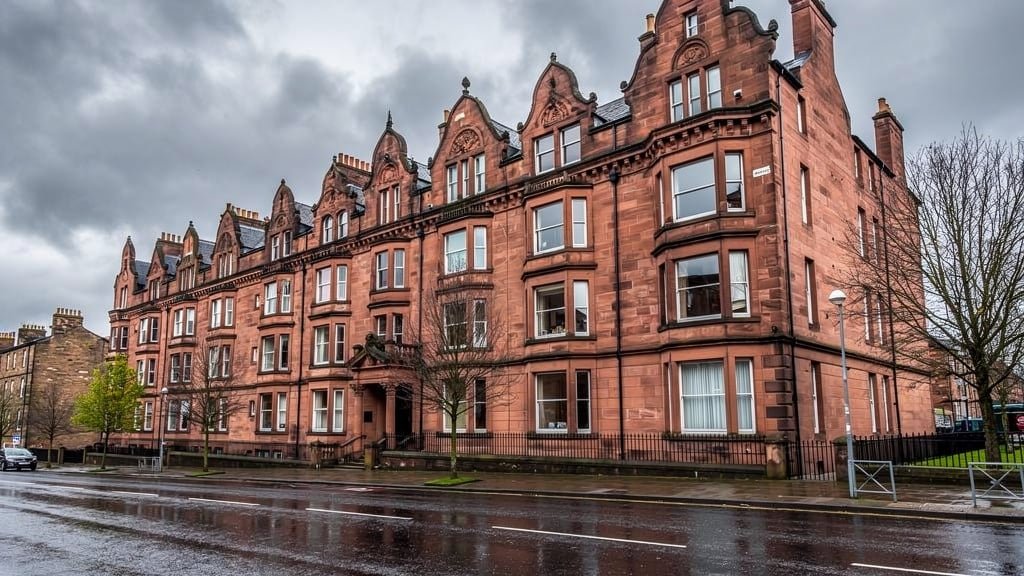 Traditional Scottish Victorian stone tenement building in Glasgow showing red sandstone masonry and architectural details in overcast weather